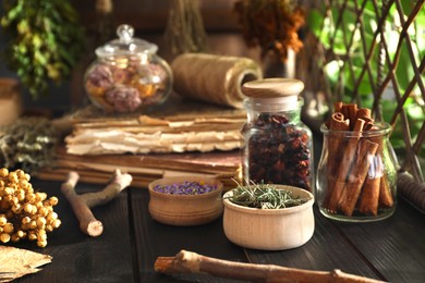 Photo of Different dry herbs and flowers on black wooden table indoors