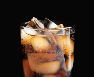 Photo of Glass of tasty refreshing cola with ice cubes on black background