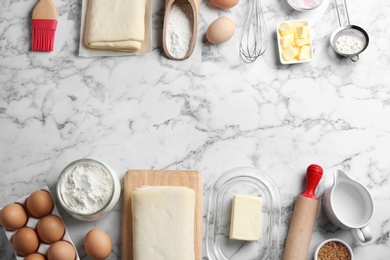 Frame made with puff pastry dough and ingredients on white marble table, flat lay. Space for text