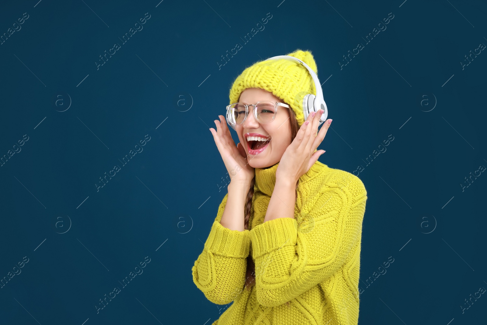 Photo of Young woman listening to music with headphones on dark blue background