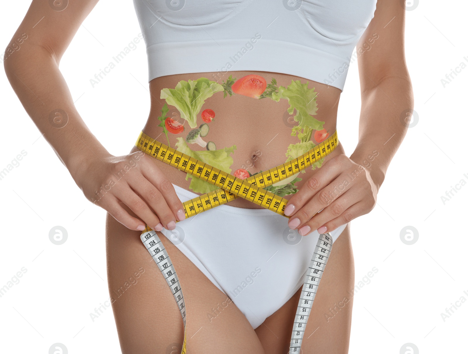 Image of Young woman measuring waist with tape and images of vegetables on her belly against white background. Healthy eating