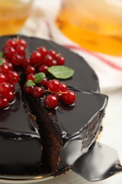 Tasty homemade chocolate cake with berries and mint on white table, closeup