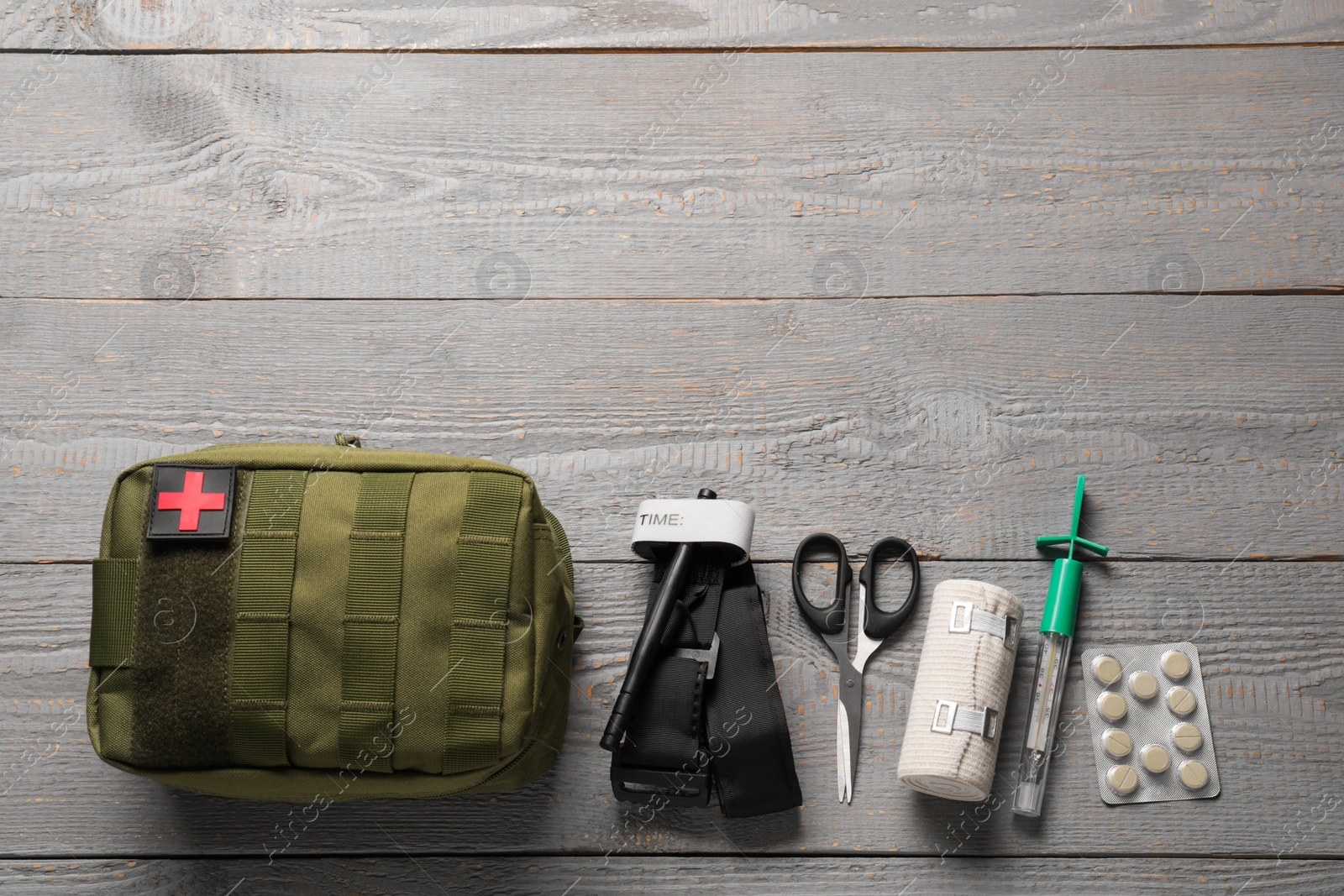 Photo of Flat lay composition with military first aid kit and tourniquet on light grey wooden table. Space for text