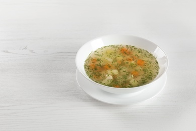 Photo of Bowl of fresh homemade soup to cure flu on wooden background