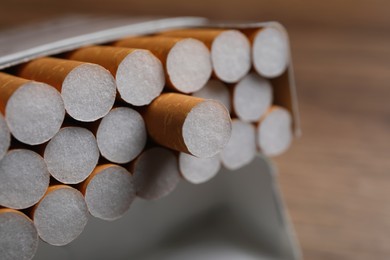 Photo of Cigarettes with orange filters in pack on table, closeup