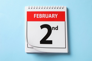 Top view of calendar with date February 2nd on light blue background. Groundhog day