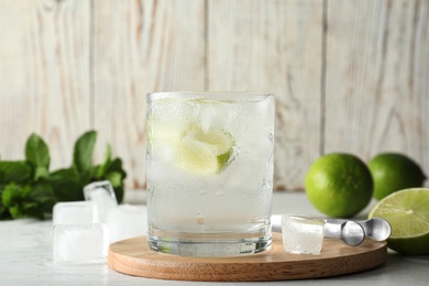 Glass of cocktail with vodka, ice and lime on wooden table