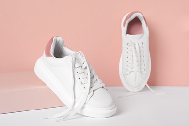Stylish sneakers with white shoe laces on color background