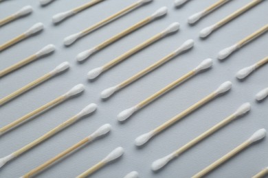 Many wooden cotton buds on light grey background, flat lay