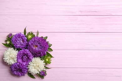 Beautiful asters and space for text on pink wooden background, flat lay. Autumn flowers