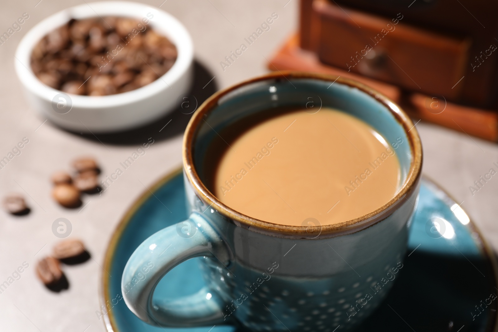 Photo of Delicious coffee with milk in cup and beans on light table, closeup