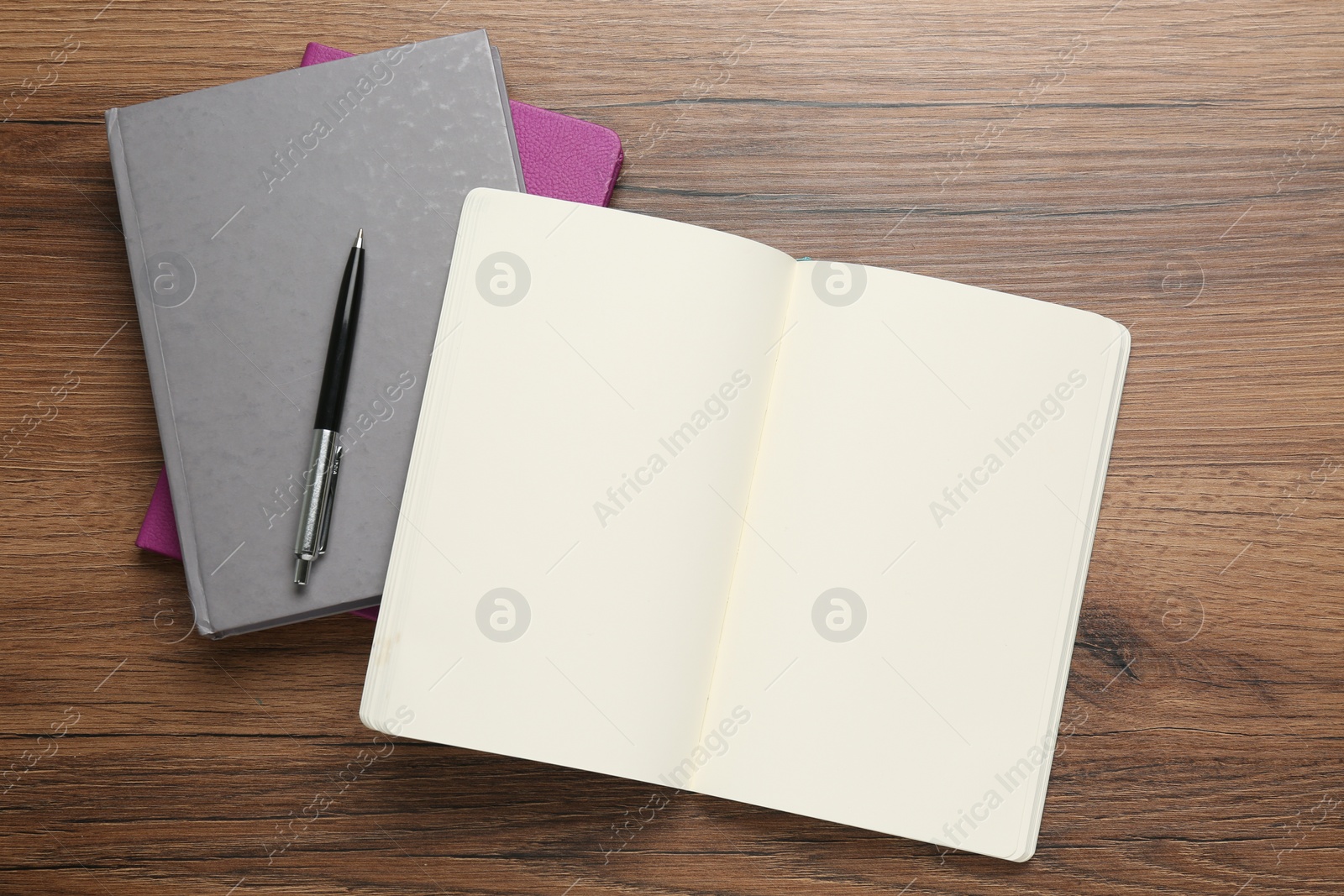 Photo of Notebooks and pen on wooden table, flat lay. Space for text