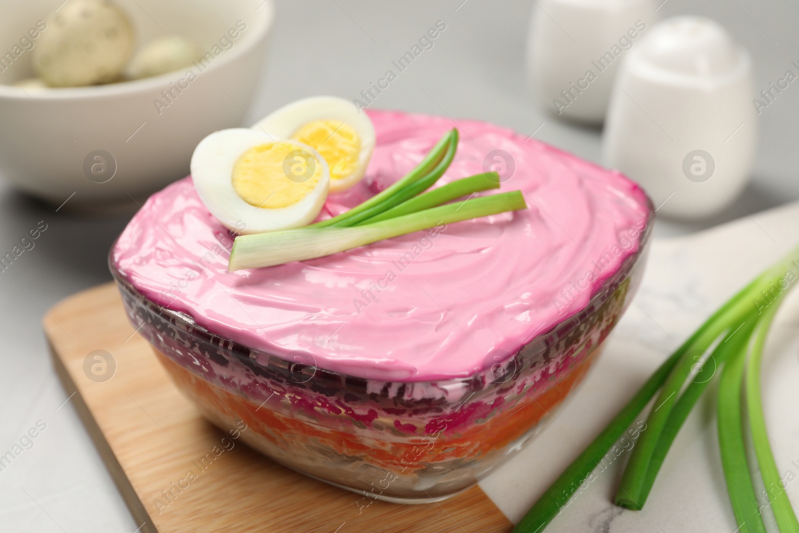 Photo of Herring under fur coat salad on white table, closeup. Traditional Russian dish