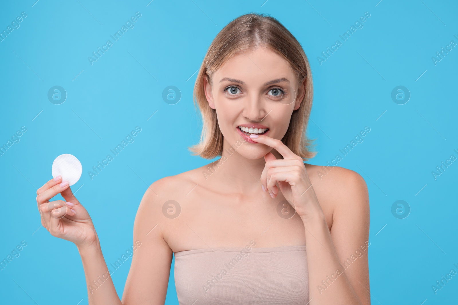 Photo of Young woman with cotton pad on light blue background