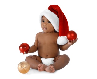 Cute African-American baby wearing Santa hat with Christmas decorations on white background