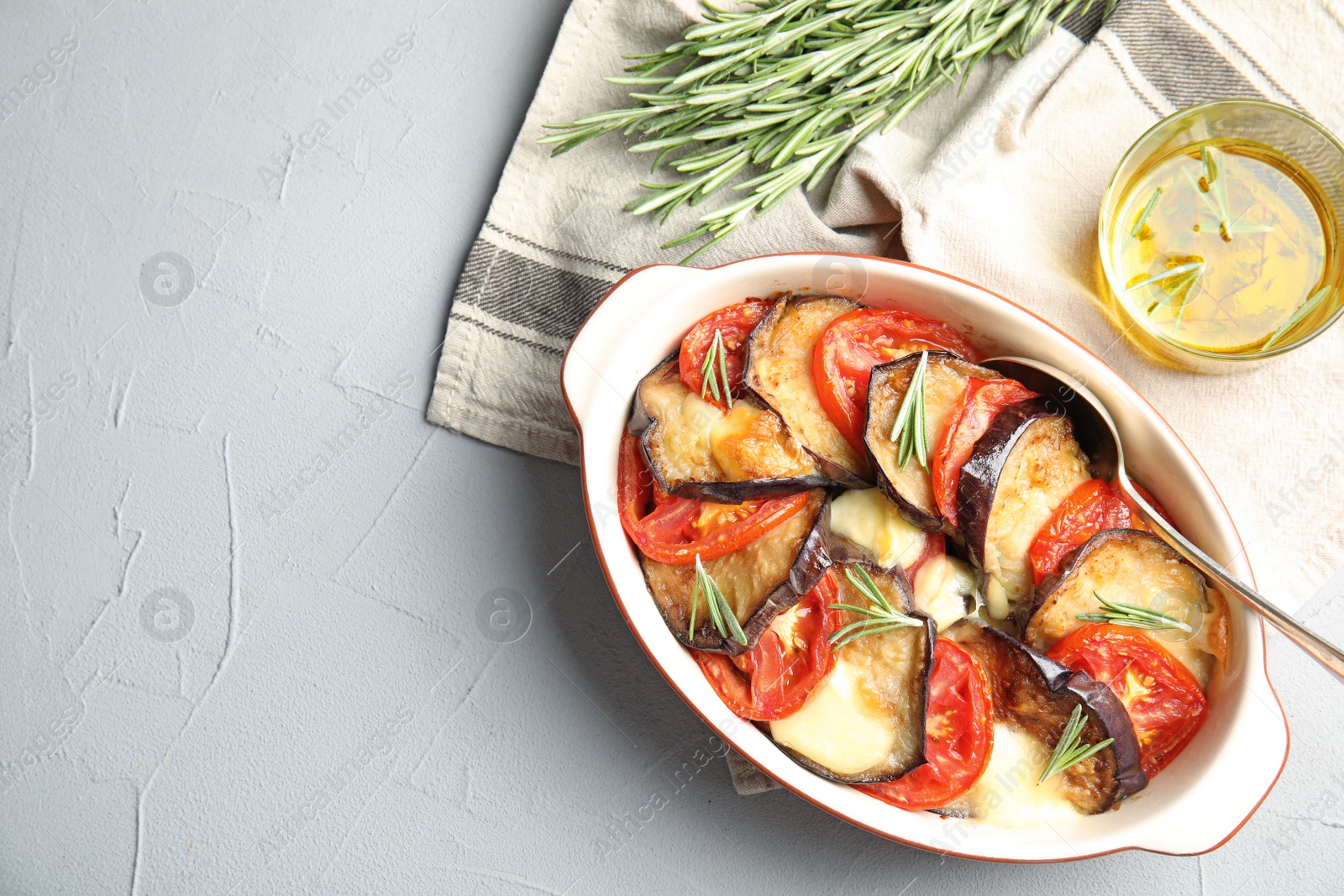 Photo of Flat lay composition with baked eggplant, tomatoes and rosemary in dishware on table. Space for text