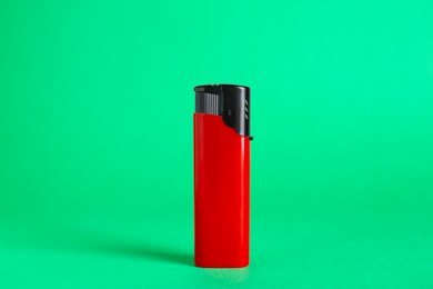 Photo of Stylish small pocket lighter on green background