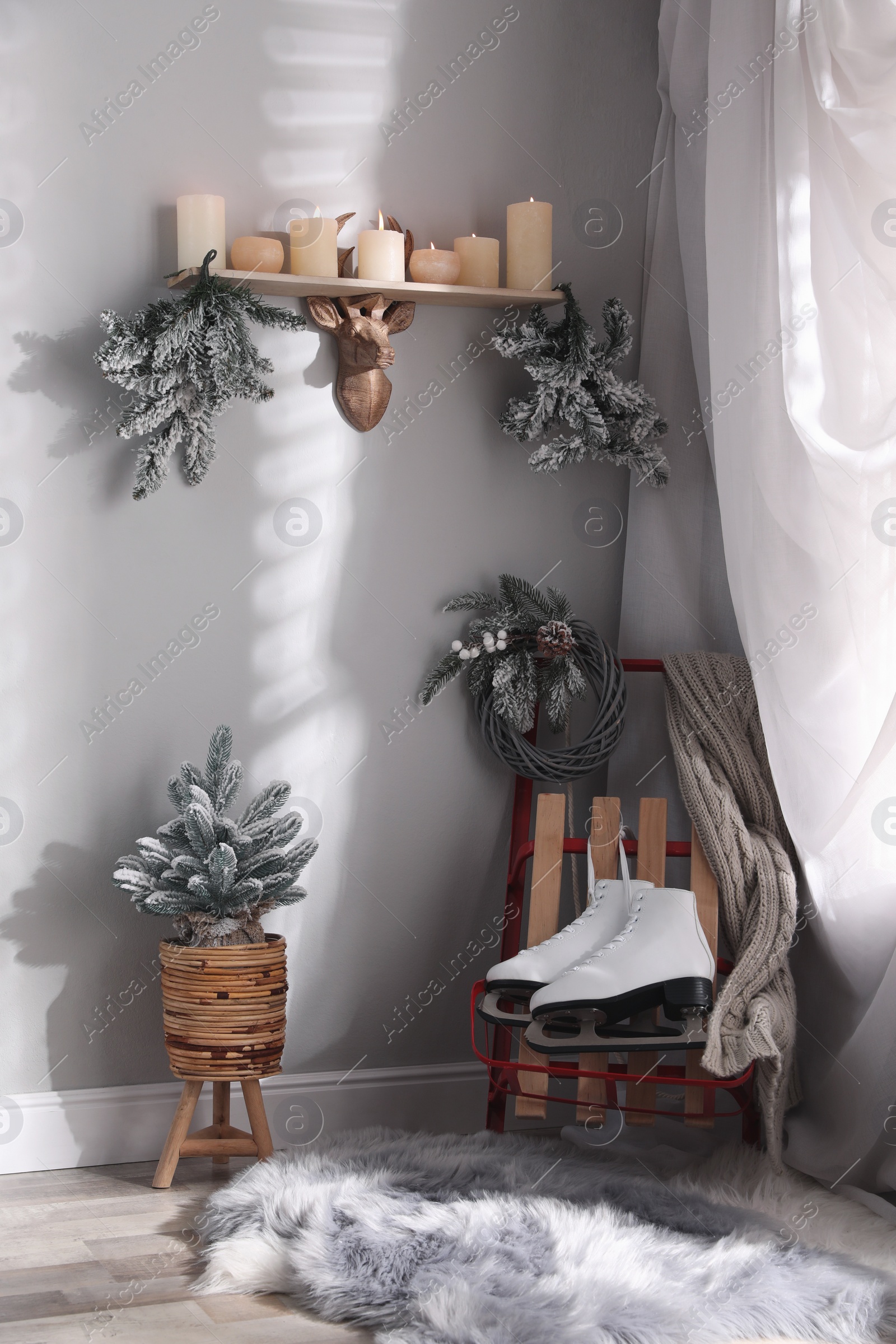 Photo of Pair of ice skates, sleigh and beautiful Christmas decor near white wall indoors