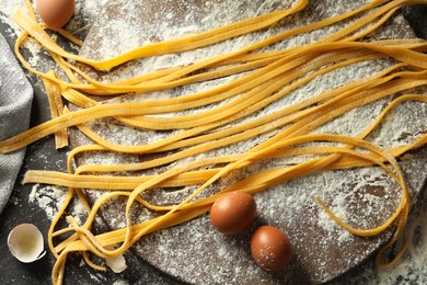 Photo of Homemade pasta, flour and eggs on dark table, flat lay