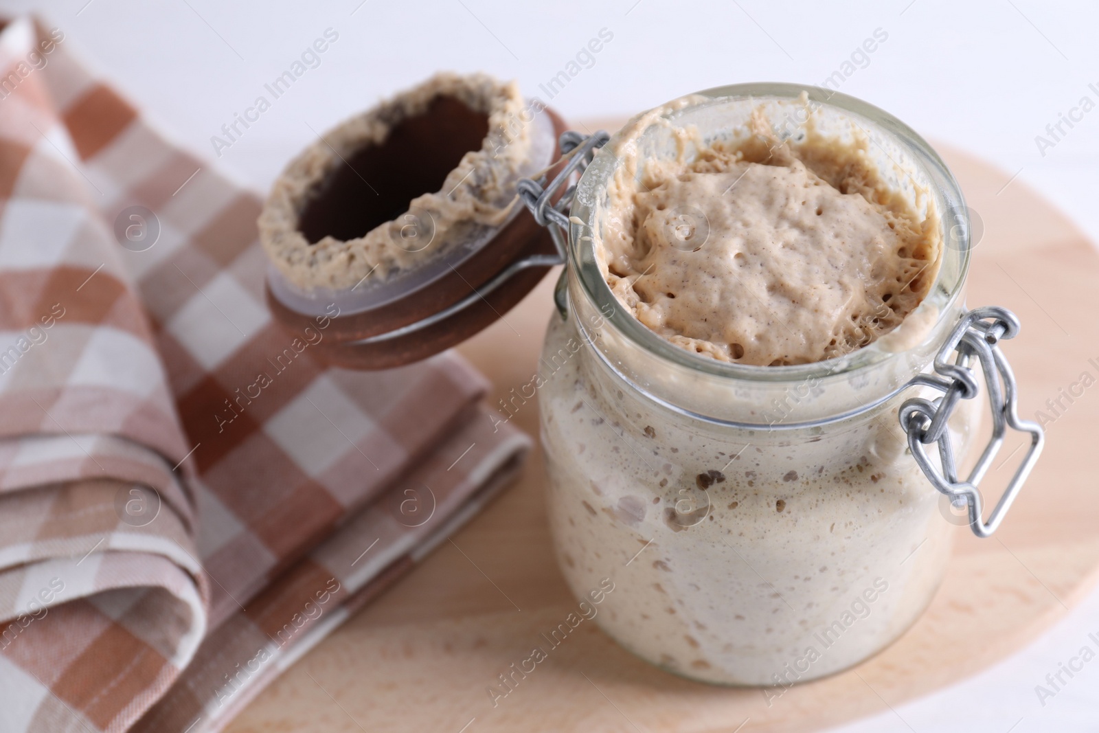 Photo of Sourdough starter in glass jar on table, closeup