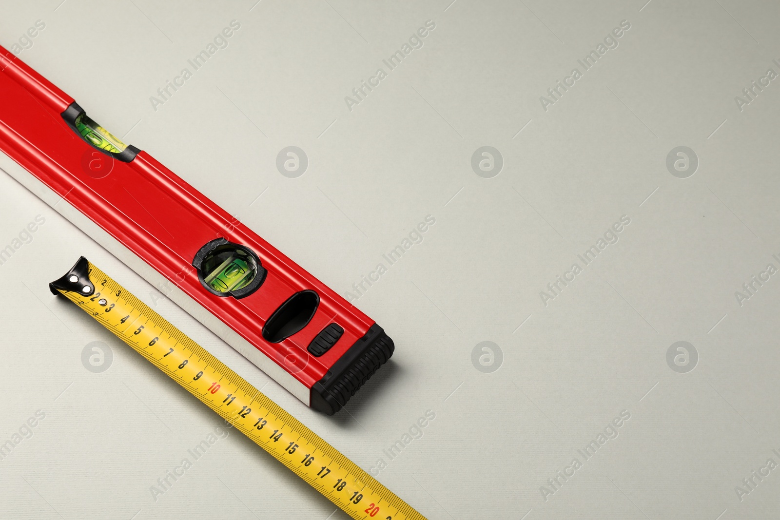 Photo of Building level and tape measure on beige background. Space for text