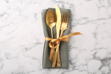 Set of stylish cutlery and napkin on white marble table, top view