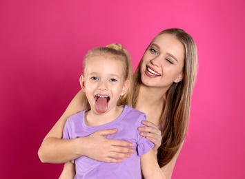 Happy mother and little daughter on pink background