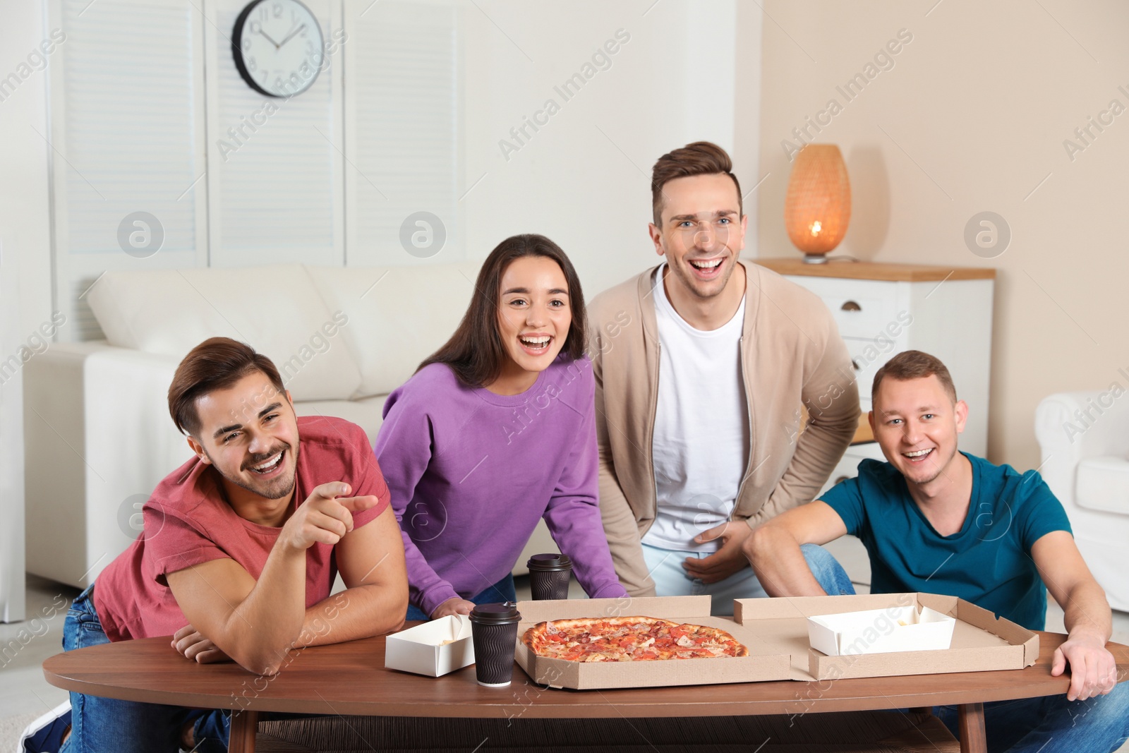 Photo of Group of friends with tasty food laughing while watching TV at home