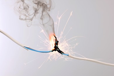 Image of Sparking electrical wire on light background, closeup