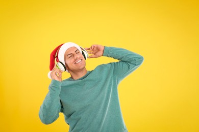 Photo of Happy man with headphones on yellow background. Christmas music