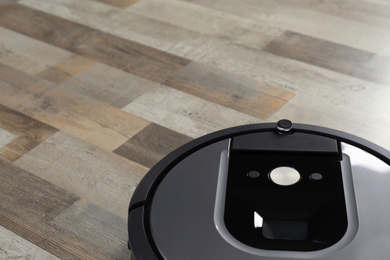 Modern robotic vacuum cleaner on wooden floor
