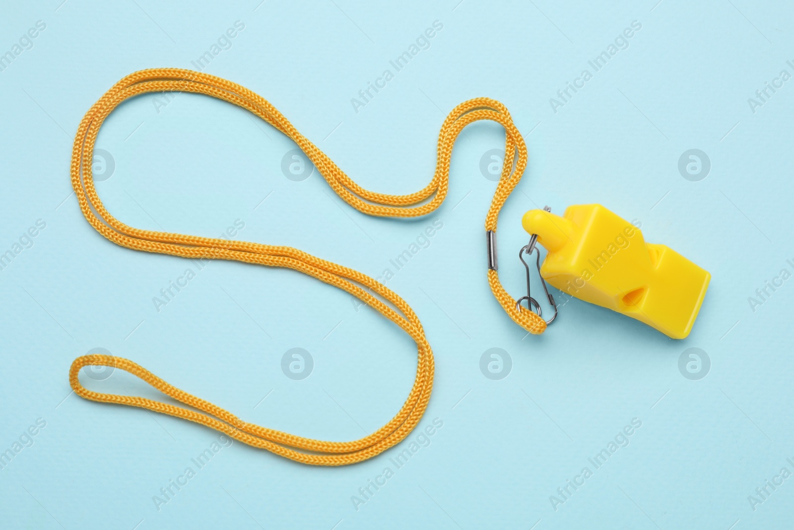 Photo of One yellow whistle with cord on light blue background, top view