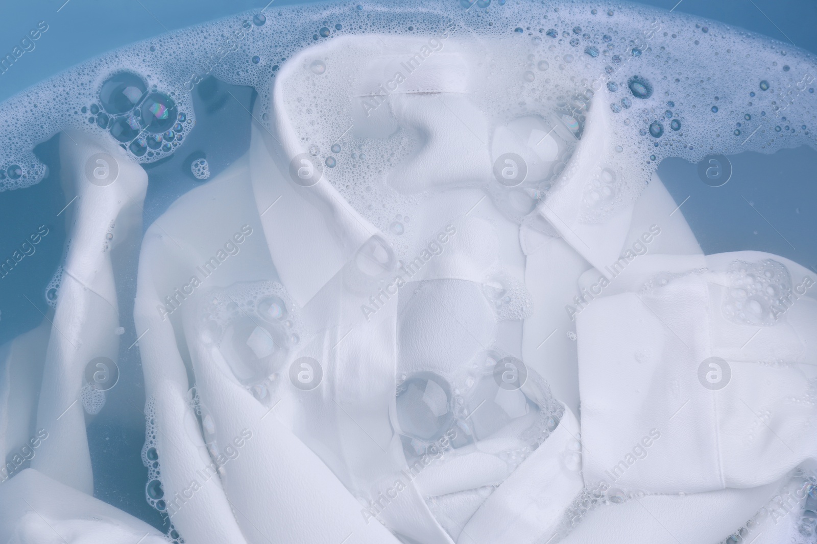 Photo of White clothing in suds, top view. Hand washing laundry