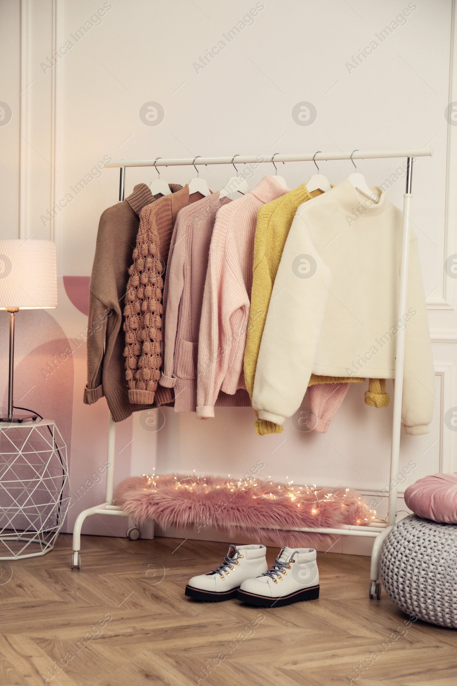 Photo of Rack with stylish warm clothes and shoes in modern dressing room