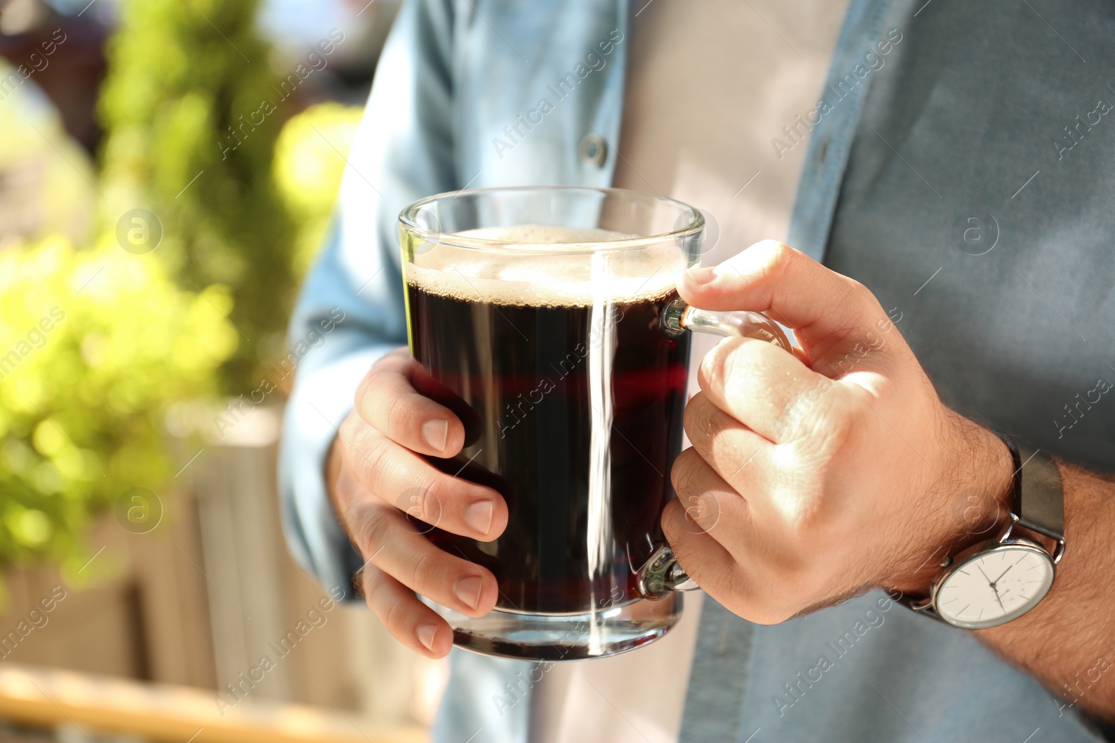 Photo of Young man with cold kvass outdoors, closeup. Traditional Russian summer drink