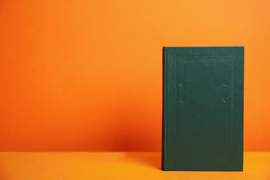 Hardcover book on orange background. Space for design