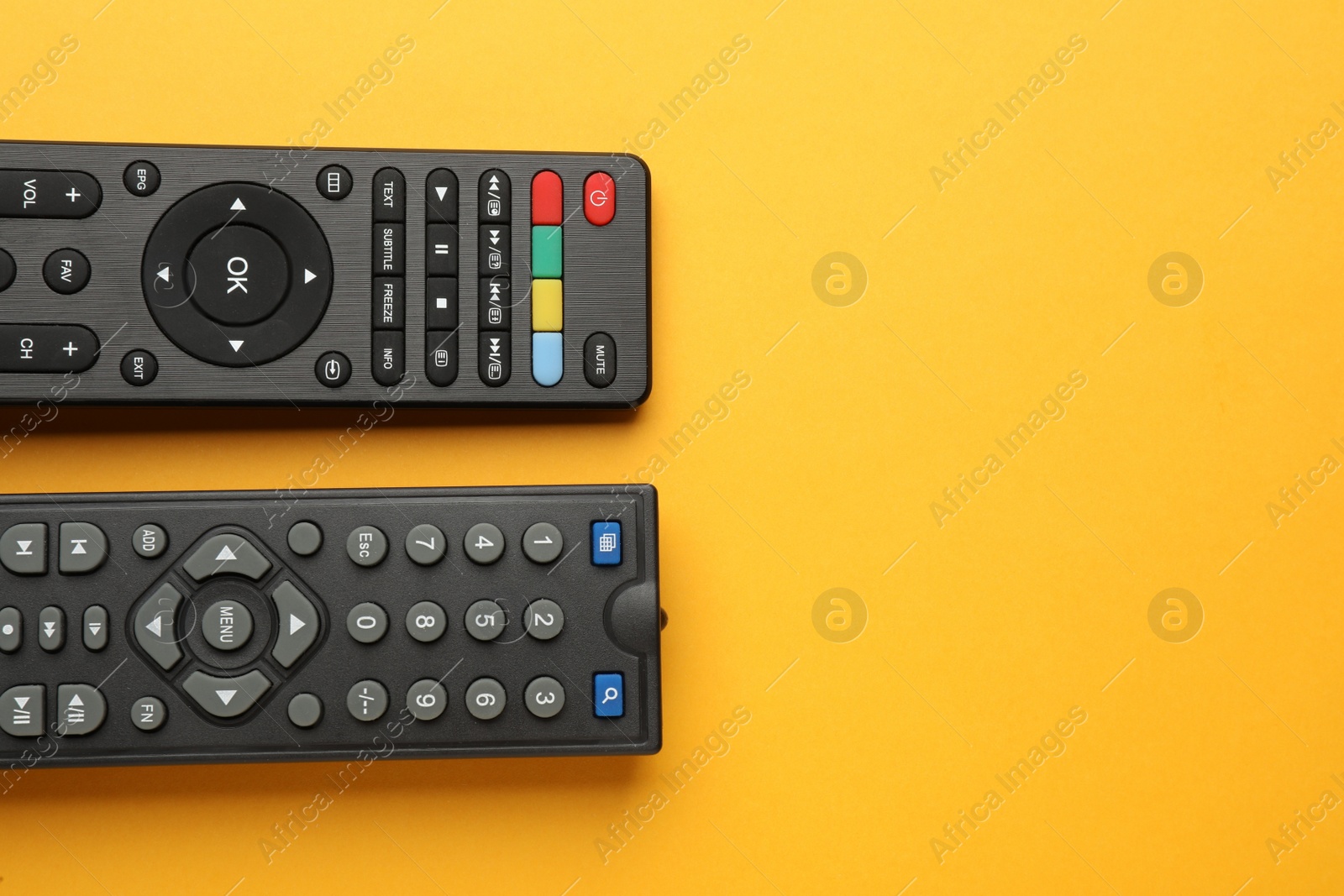 Photo of Remote controls on yellow background, flat lay. Space for text