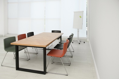 Photo of Conference room interior with wooden table and flipchart