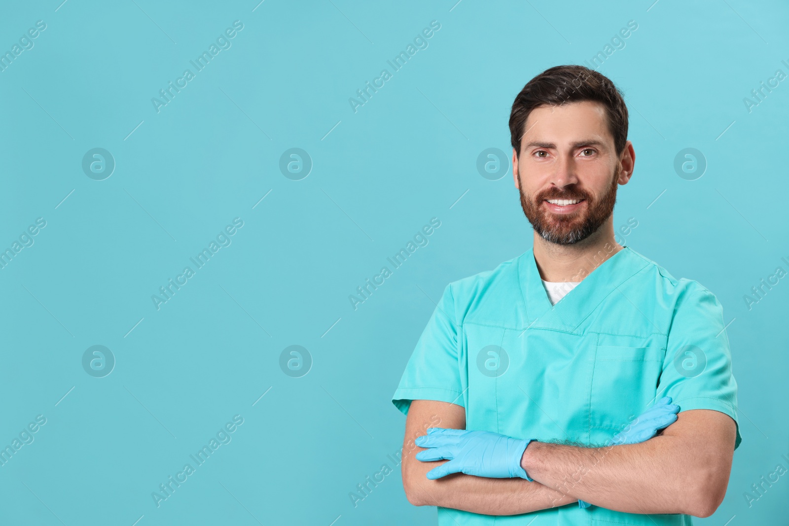 Photo of Happy nurse in medical uniform on light blue background, space for text