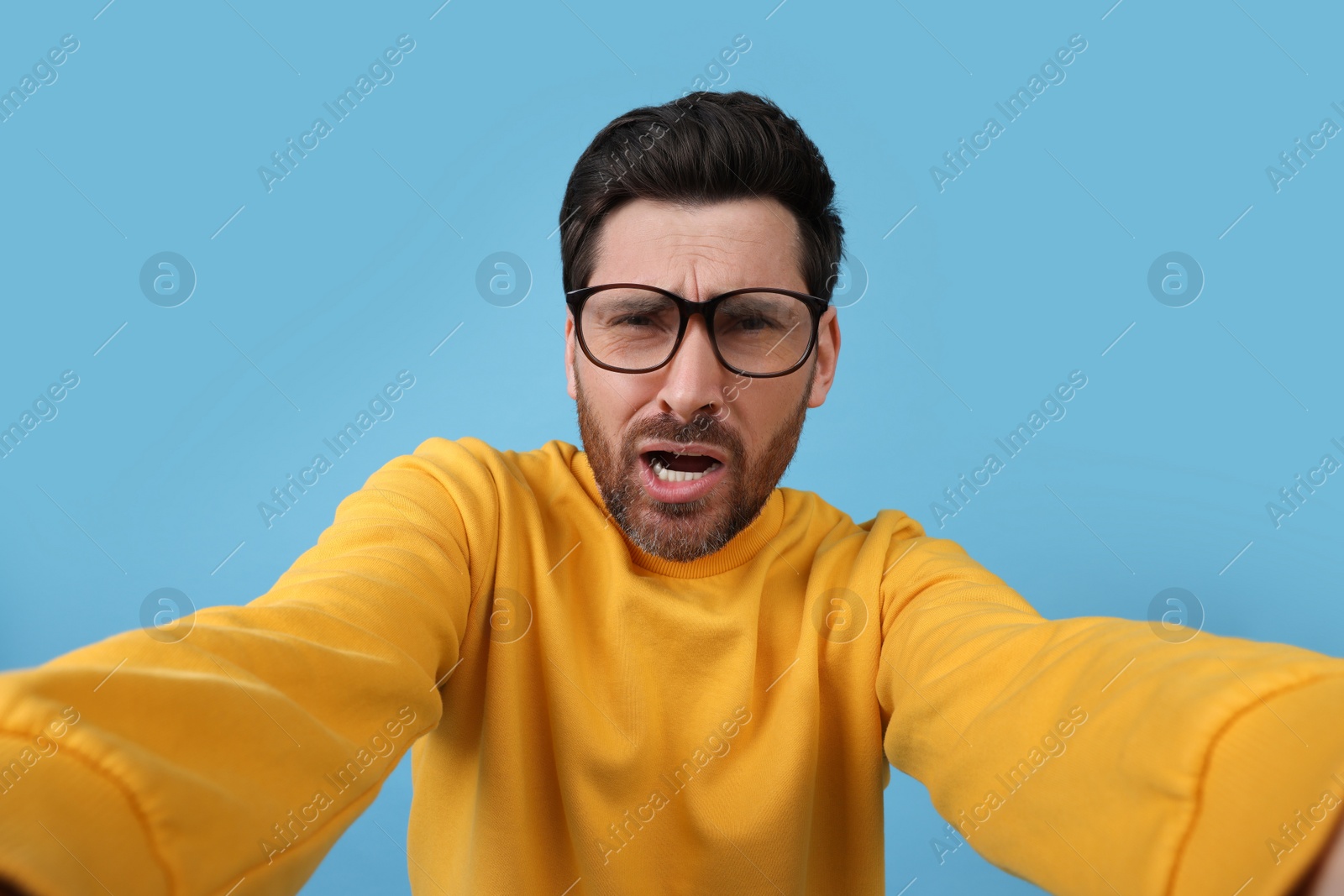 Photo of Emotional man taking selfie on light blue background