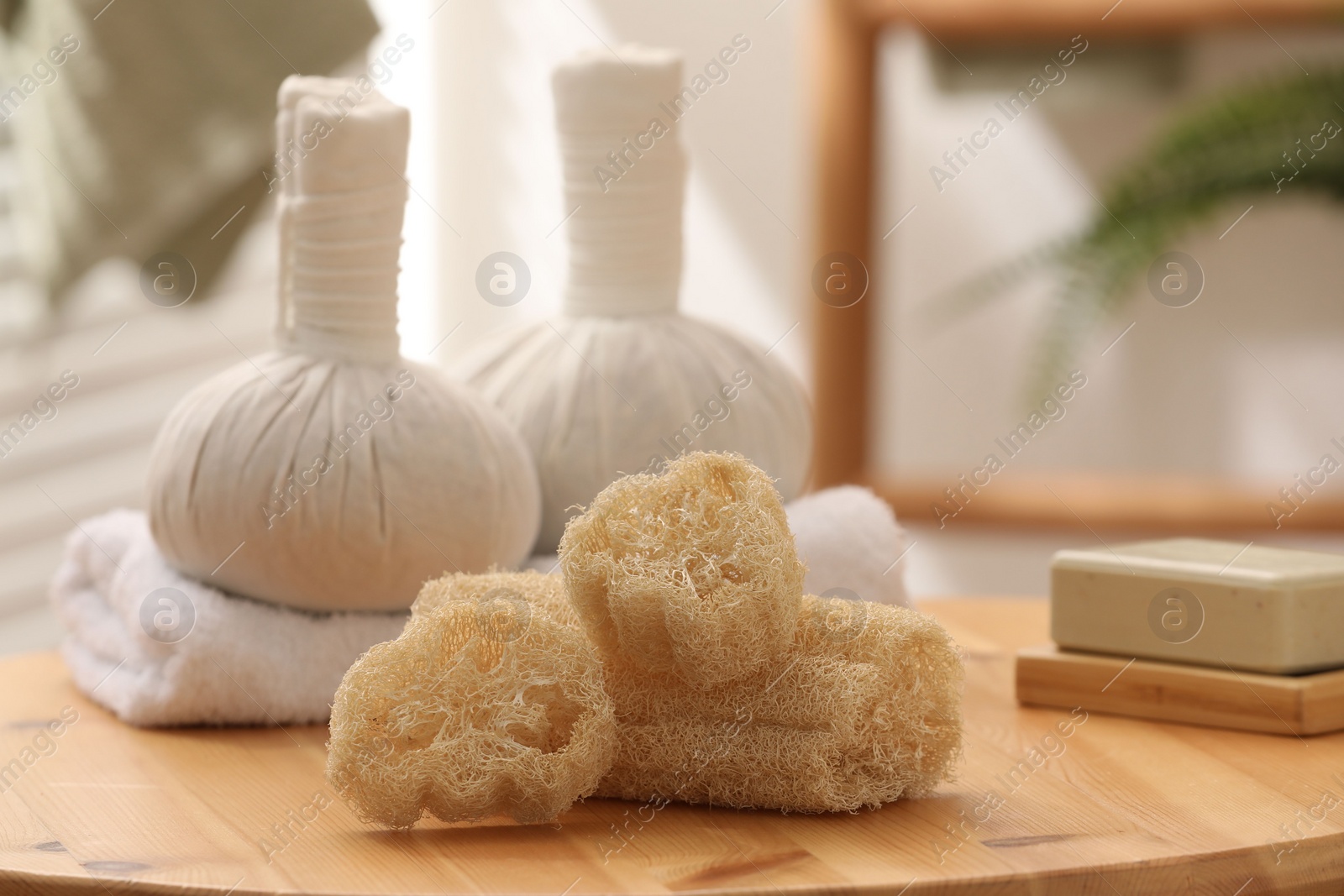 Photo of Loofah sponges, soap and herbal bags on wooden table indoors, closeup