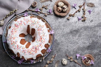 Photo of Glazed Easter cake with sprinkles and quail eggs on grey table, flat lay. Space for text