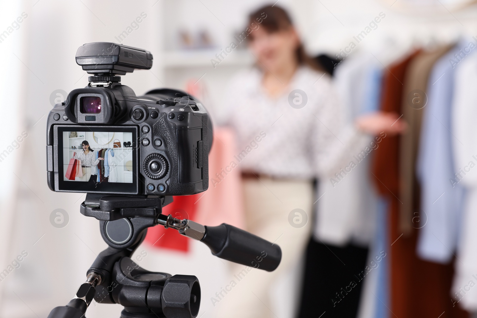 Photo of Fashion blogger with shopping bags recording video at home, focus on camera