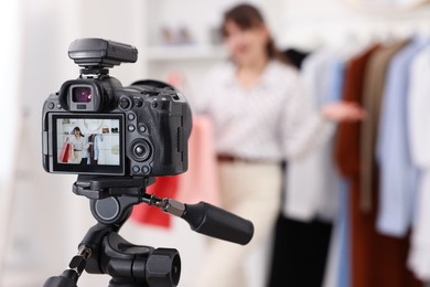 Fashion blogger with shopping bags recording video at home, focus on camera