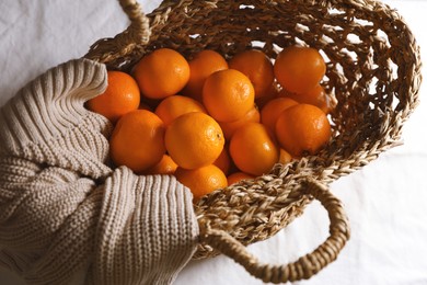 Net bag with fresh ripe tangerines on white cloth, top view