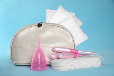 Bag with menstrual pads and other hygiene products on light blue background