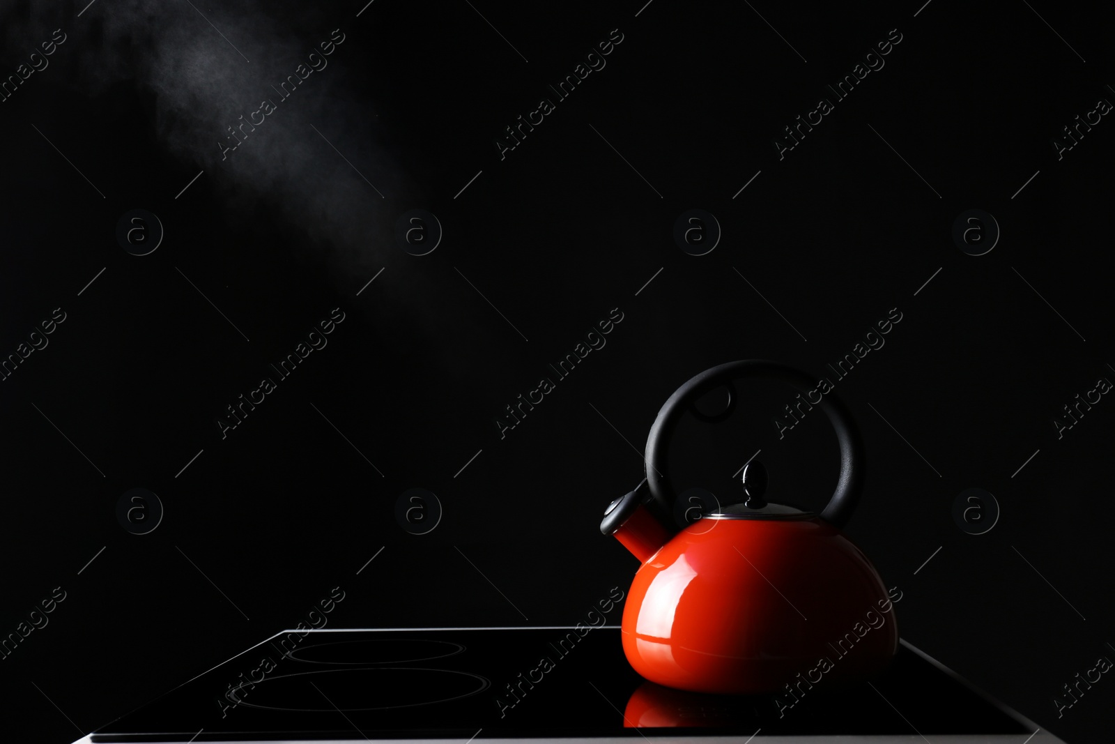 Photo of Modern kettle with whistle on stove against black background, space for text