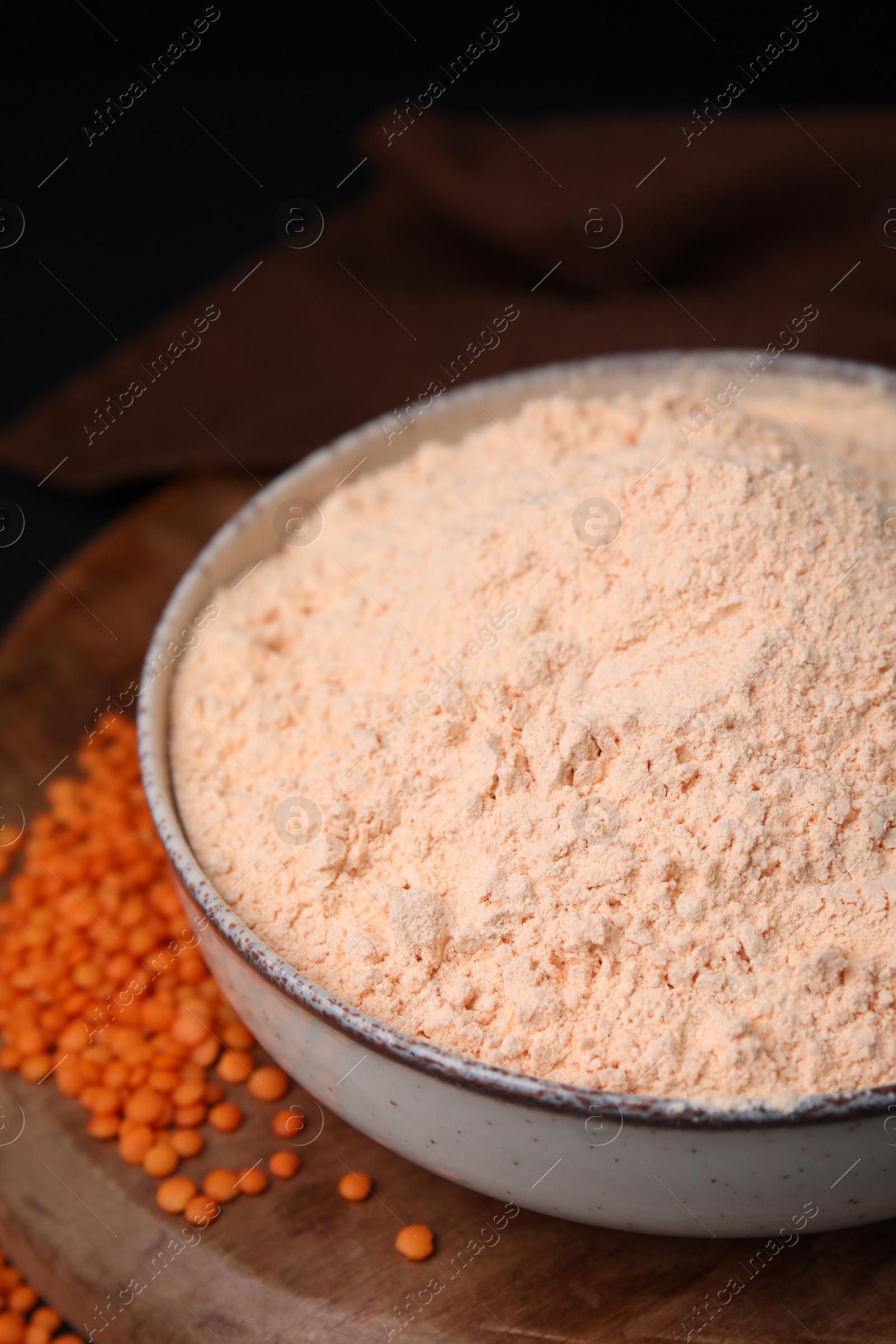 Photo of Bowl of lentil flour and seeds on wooden board, closeup