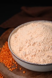 Photo of Bowl of lentil flour and seeds on wooden board, closeup