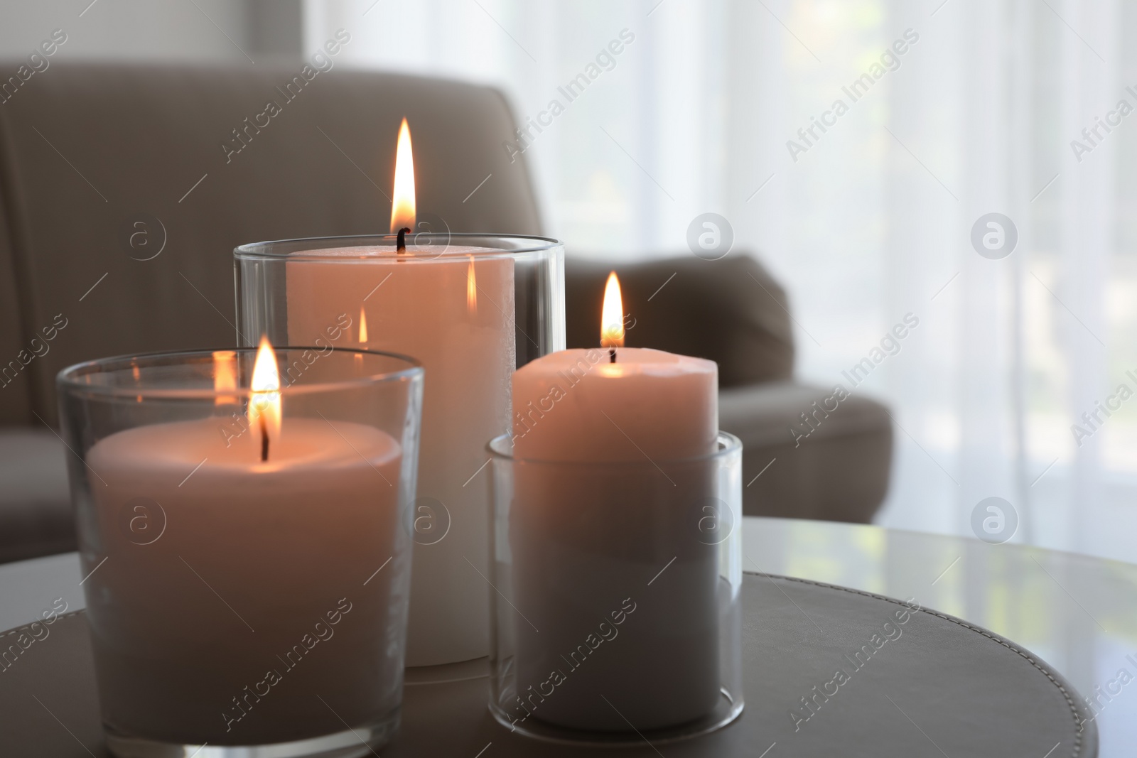 Photo of Burning candles in glass holders on table indoors. Space for text